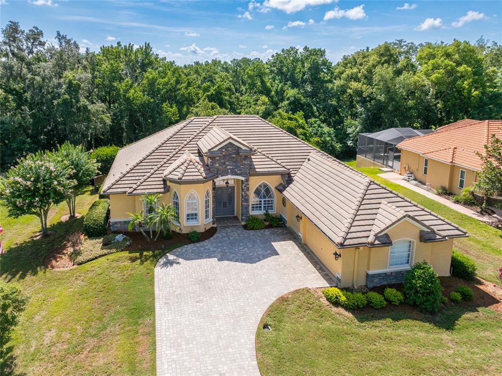 An aerial view of a single-story tan house with a stone facade and tiled roof — 13152 TRADITION DRIVE, DADE CITY, FL