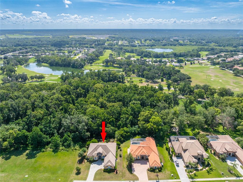 An aerial view shows a suburban house with a red arrow pointing to its roof — 13152 TRADITION DRIVE, DADE CITY, FL