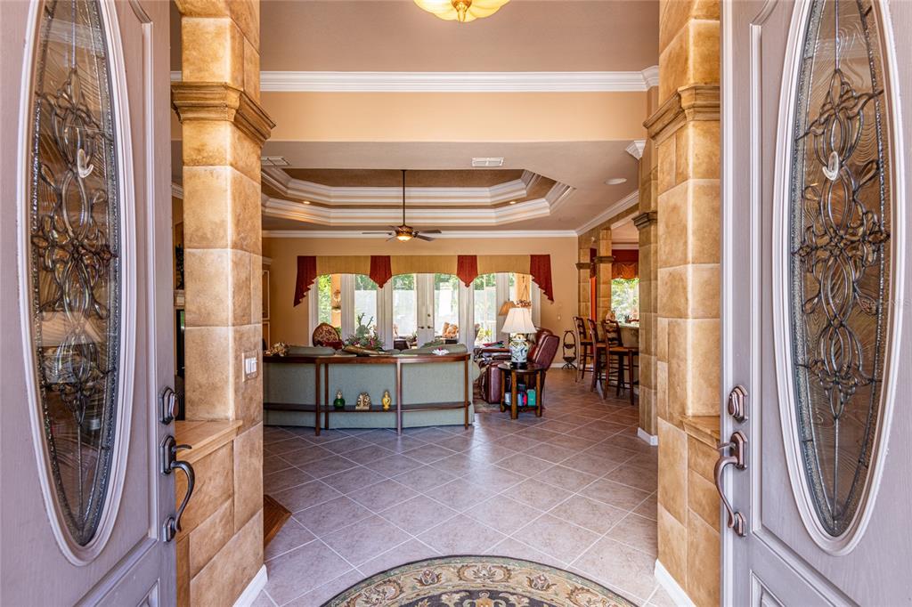 A view from an entryway into a living room with tiled floors and tray ceilings — 13152 TRADITION DRIVE, DADE CITY, FL