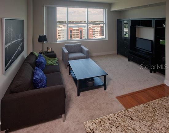 A living room features a dark sofa, a coffee table, and a large entertainment center — 1208 E KENNEDY BOULEVARD UNIT 1120, TAMPA, FL