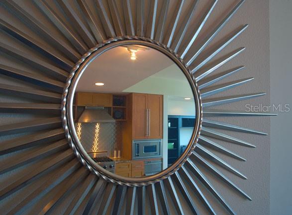 A sunburst mirror reflects a kitchen with wooden cabinets, stainless steel appliances, and tile backsplash — 1208 E KENNEDY BOULEVARD UNIT 1120, TAMPA, FL