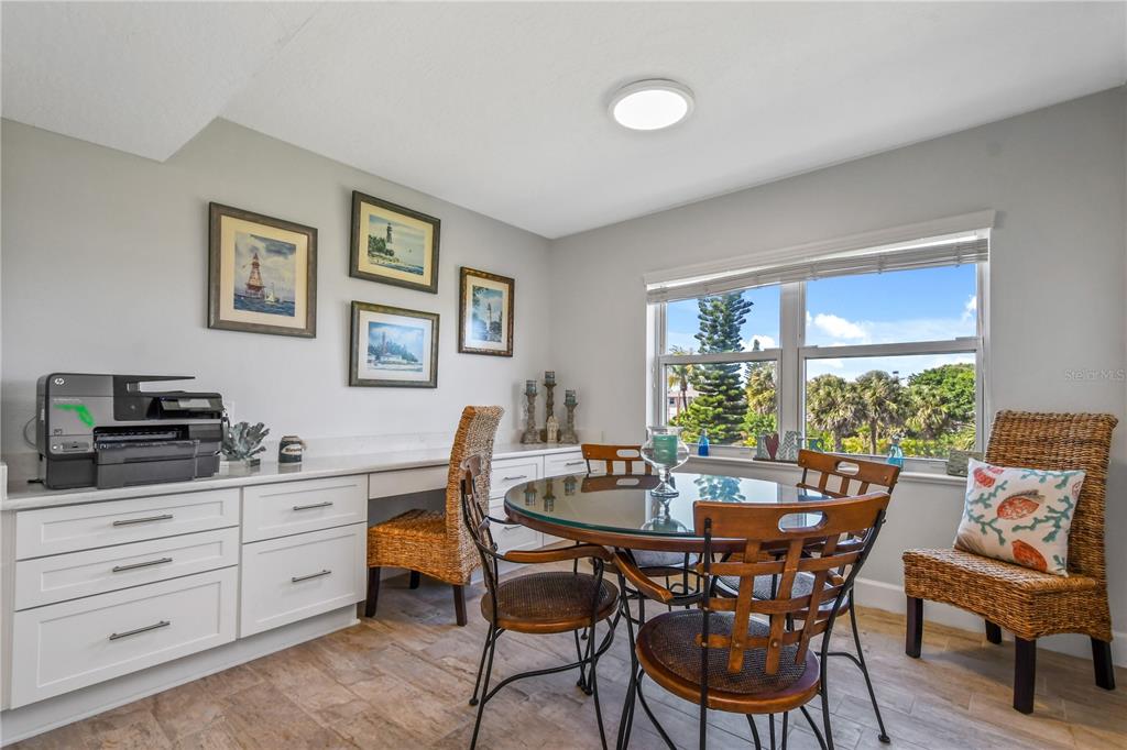 A dining area features a glass-topped table, wicker chairs, built-in cabinetry, and a large window — 8700 RIDGEWOOD AVENUE UNIT B204, CAPE CANAVERAL, FL