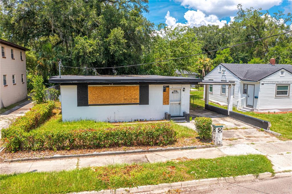 A single-story white house with boarded-up windows and a flat roof sits on a street — 1651 W 34 STREET, JACKSONVILLE, FL