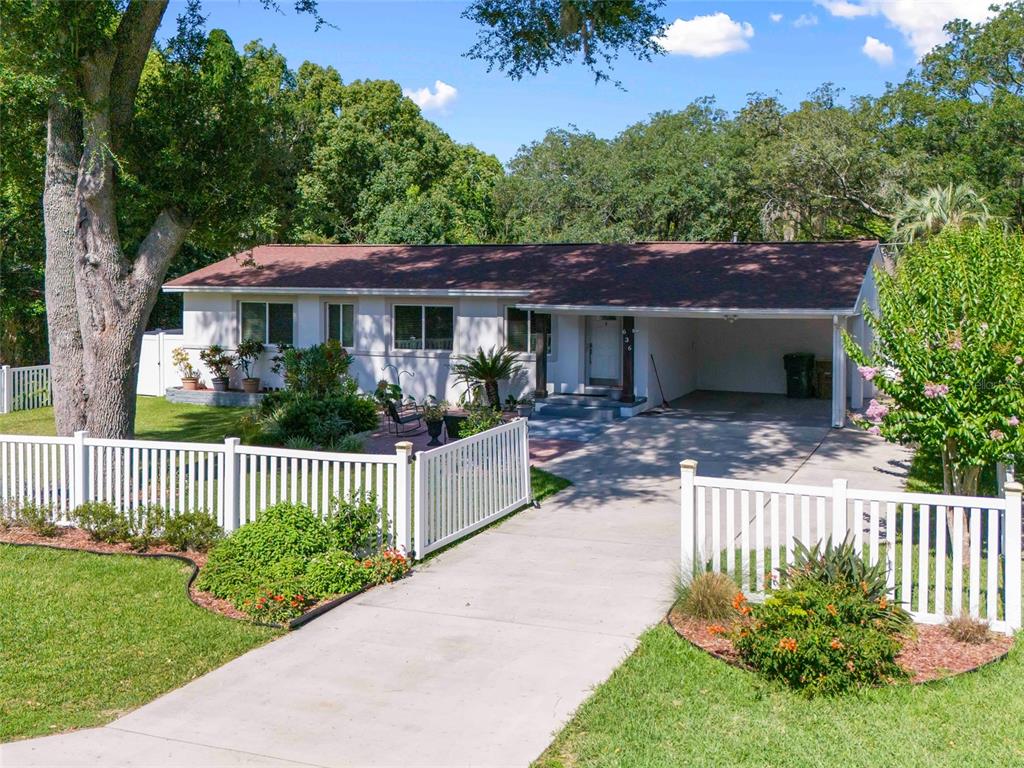 A single-story house with a white exterior, a carport, and a white picket fence — 636 SE 31ST TERRACE, OCALA, FL