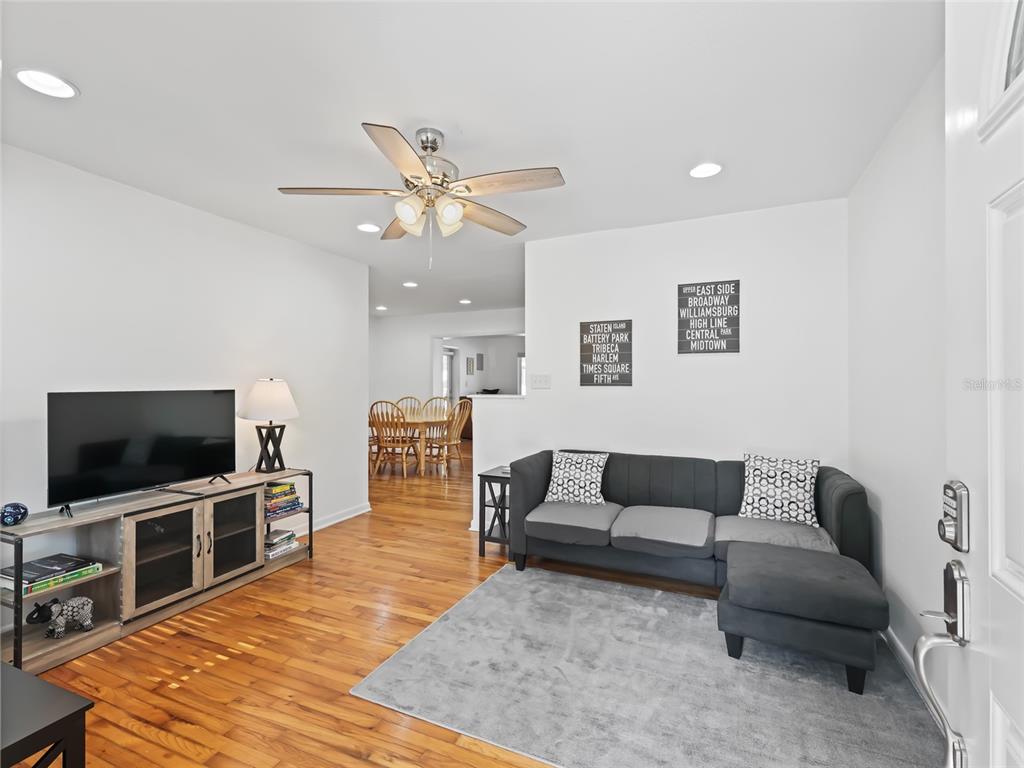 A living room with hardwood floors, a grey sectional sofa, and a television console — 636 SE 31ST TERRACE, OCALA, FL