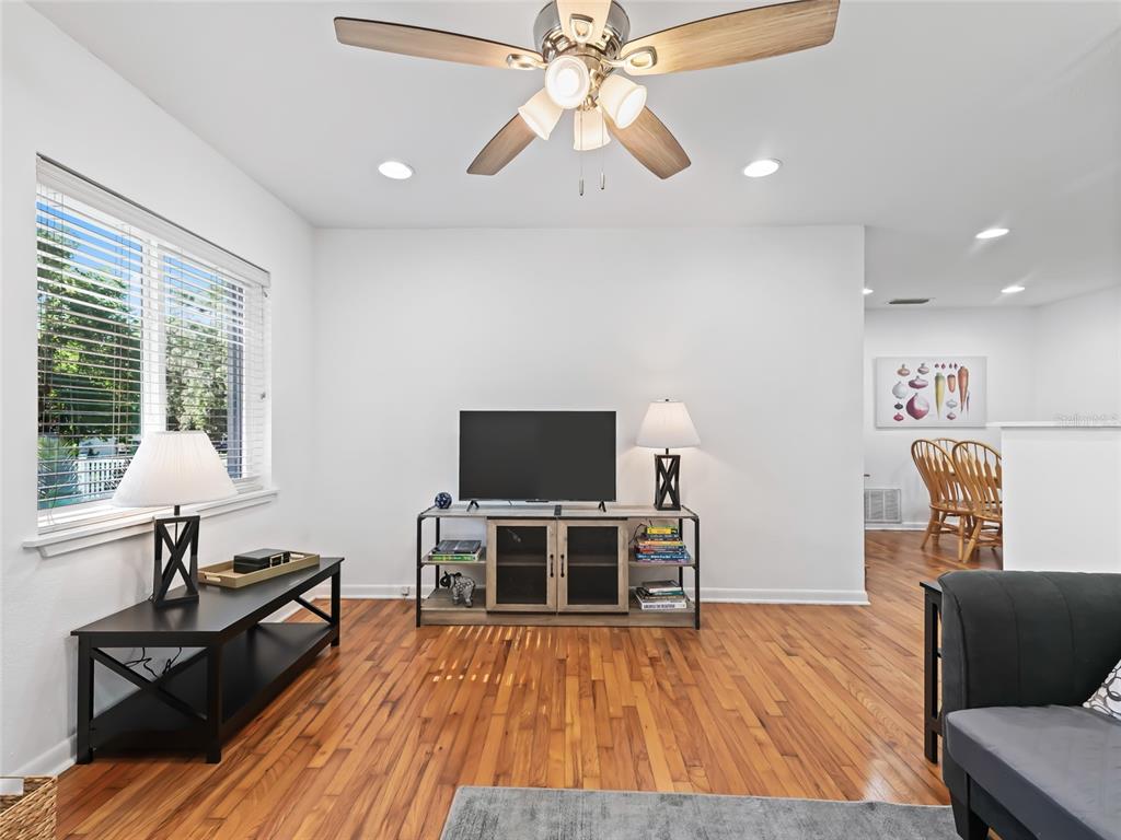 A living room features hardwood floors, a ceiling fan, a television console, and a window — 636 SE 31ST TERRACE, OCALA, FL