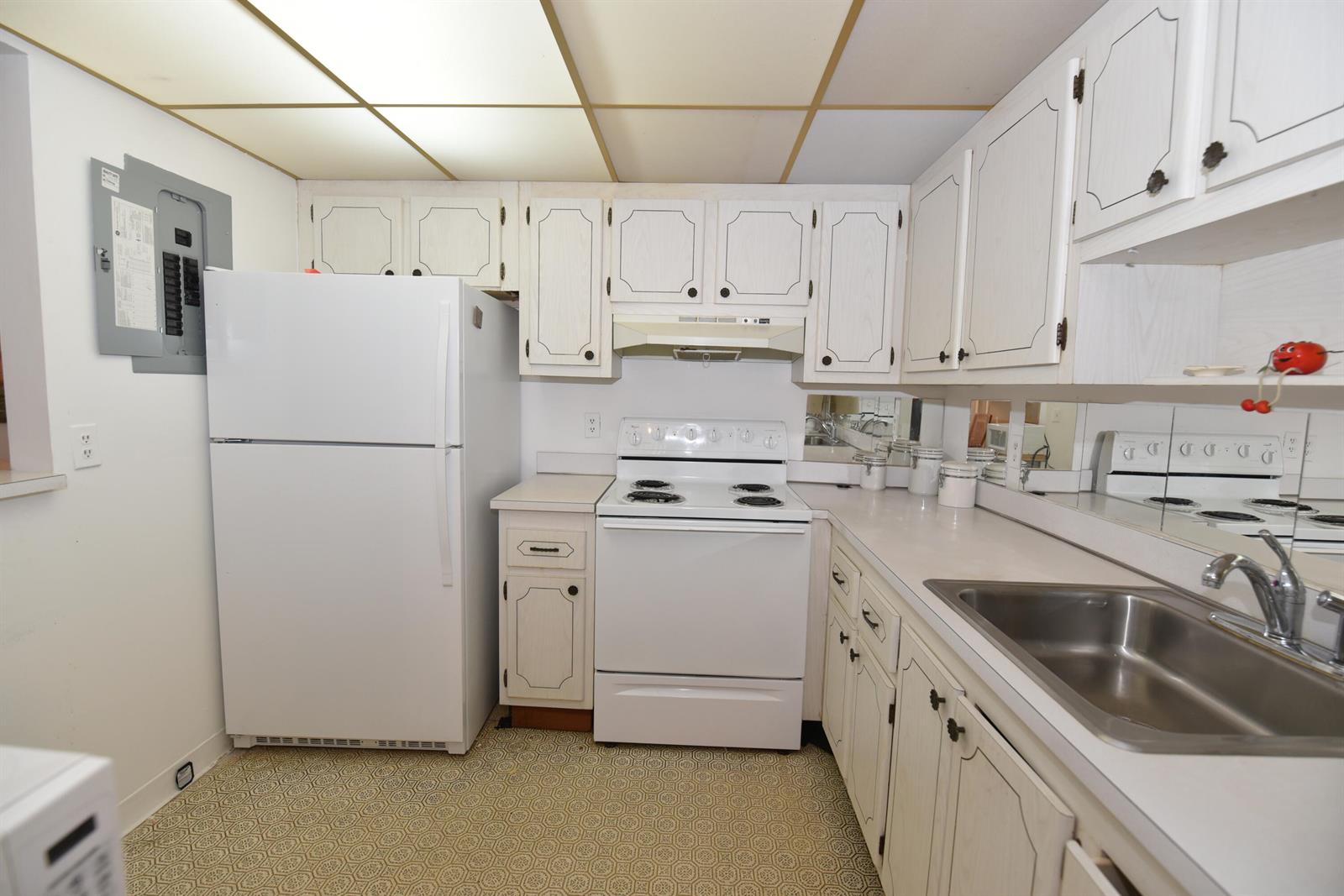 A kitchen features white appliances, light-colored wooden cabinets, a stainless steel sink, and patterned flooring — 715 Saxony O, Delray Beach FL 33446, DELRAY BEACH, FL
