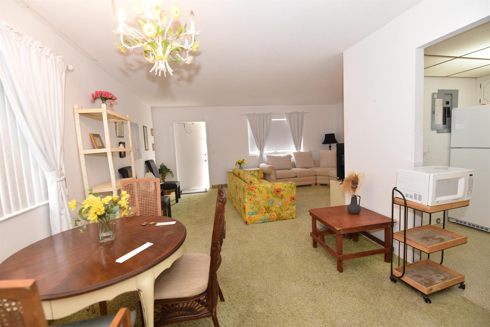A living and dining area features green carpeting, a floral sofa, and a wooden table — 715 Saxony O, Delray Beach FL 33446, DELRAY BEACH, FL