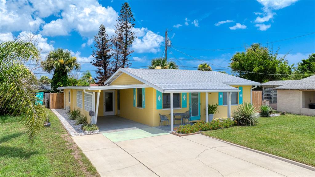 A yellow single-story house with a carport, teal shutters, and a concrete driveway — 12 OCEAN SHORE DRIVE, ORMOND BEACH, FL