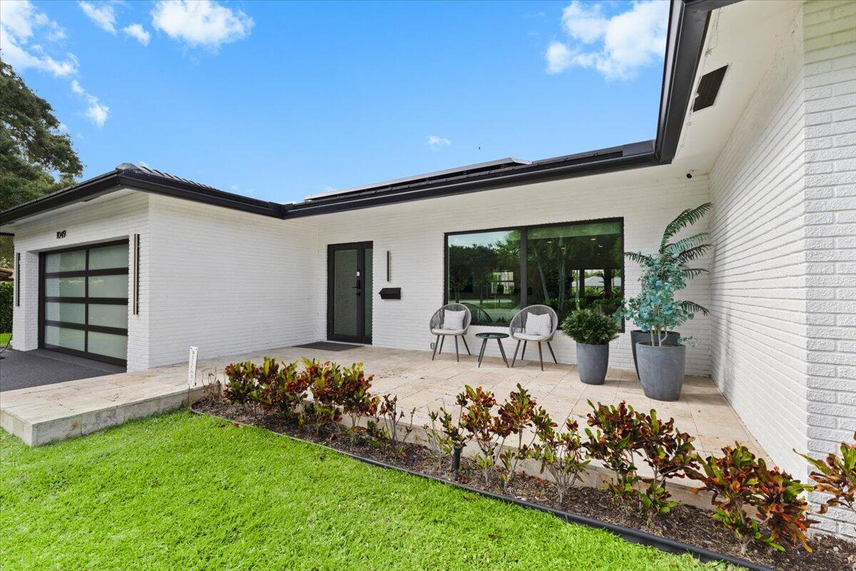 A white brick house exterior features a front patio with two chairs and a table — 1049 W Palmetto Park Road, Boca Raton FL 33486, BOCA RATON, FL