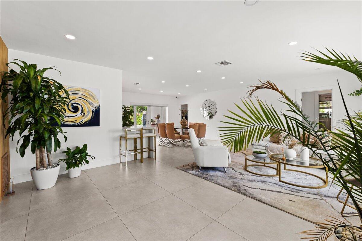 A bright, open-concept living and dining area features large floor tiles and indoor potted plants — 1049 W Palmetto Park Road, Boca Raton FL 33486, BOCA RATON, FL