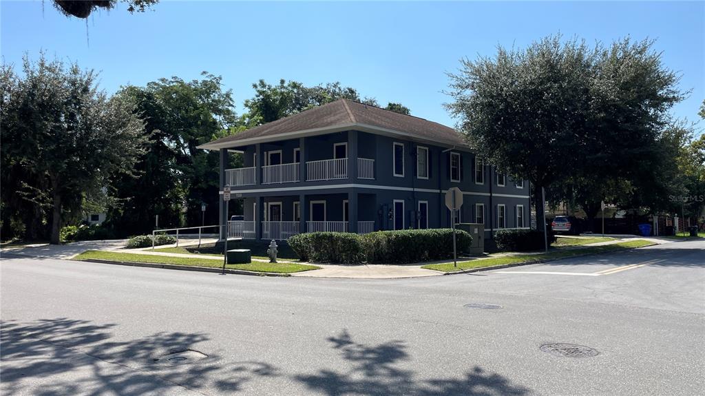A two-story gray apartment building with wrap-around balconies stands on a street corner — 722 PATRICK STREET UNIT 204, KISSIMMEE, FL