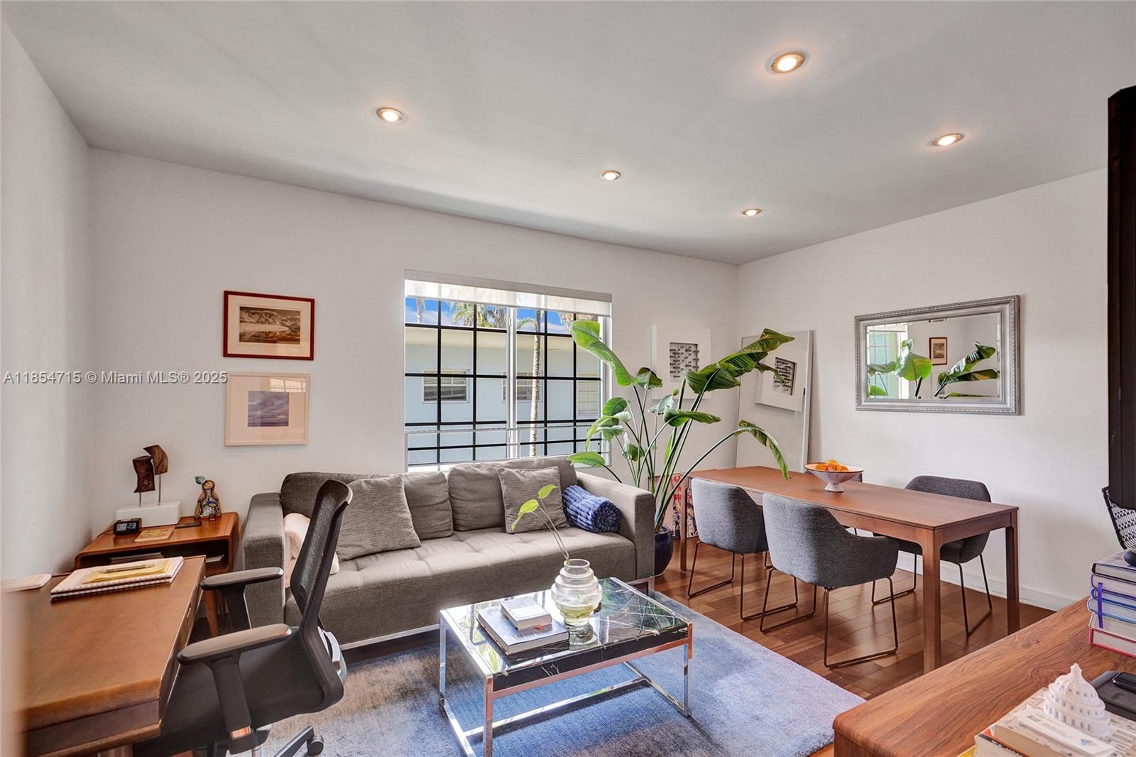 A living and dining area features a gray sofa, wooden table, and large potted plant — 815 Euclid Ave # 8, Miami Beach FL 33139, MIAMI BEACH, FL