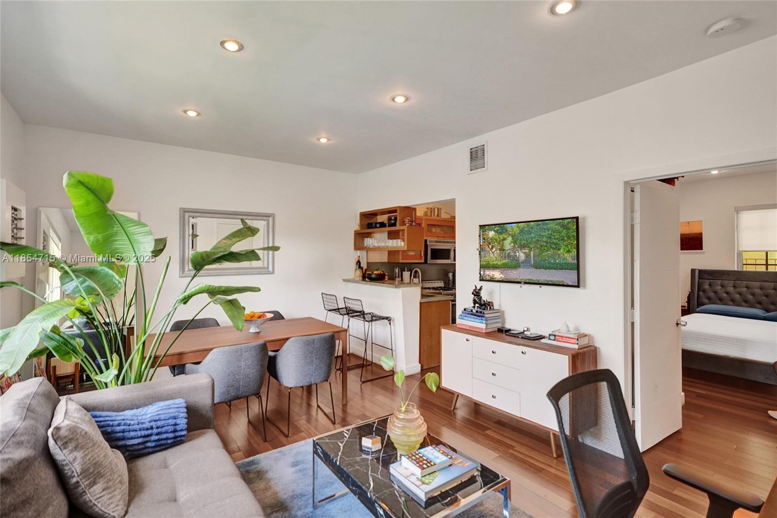 A living room with hardwood floors, a dining area, and an open kitchen with bar seating — 815 Euclid Ave # 8, Miami Beach FL 33139, MIAMI BEACH, FL