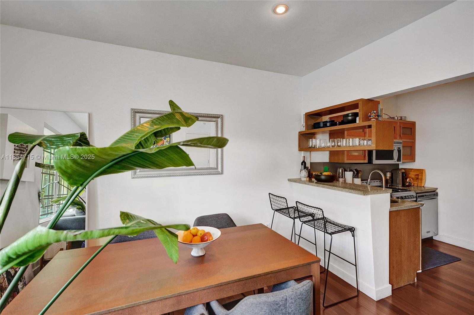 A dining area features a wooden table, a breakfast bar with stools, and open shelving — 815 Euclid Ave # 8, Miami Beach FL 33139, MIAMI BEACH, FL