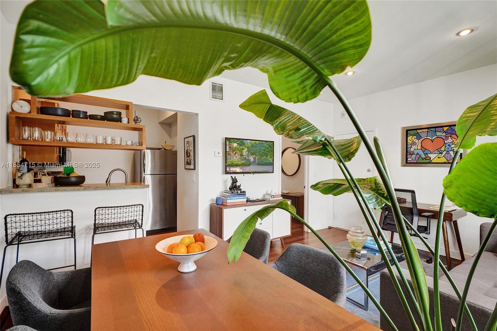 A dining area and living room feature a wooden table, modern chairs, and a kitchen — 815 Euclid Ave # 8, Miami Beach FL 33139, MIAMI BEACH, FL