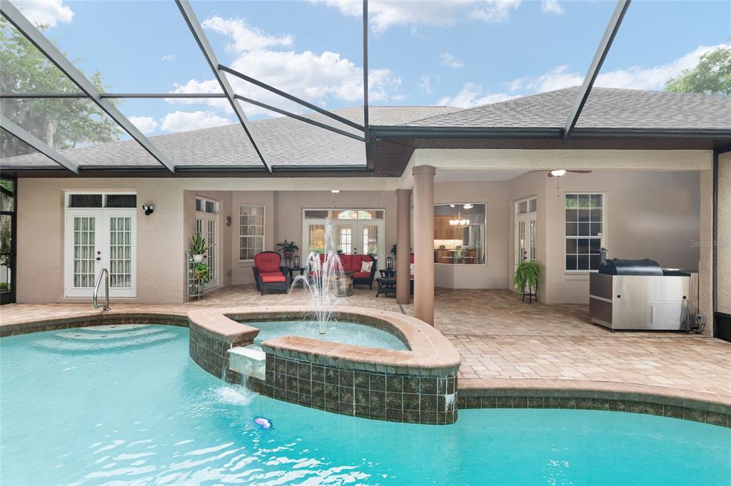 A covered patio features a pool with a fountain and a built-in outdoor grill — 19654 SW 88TH LOOP, DUNNELLON, FL