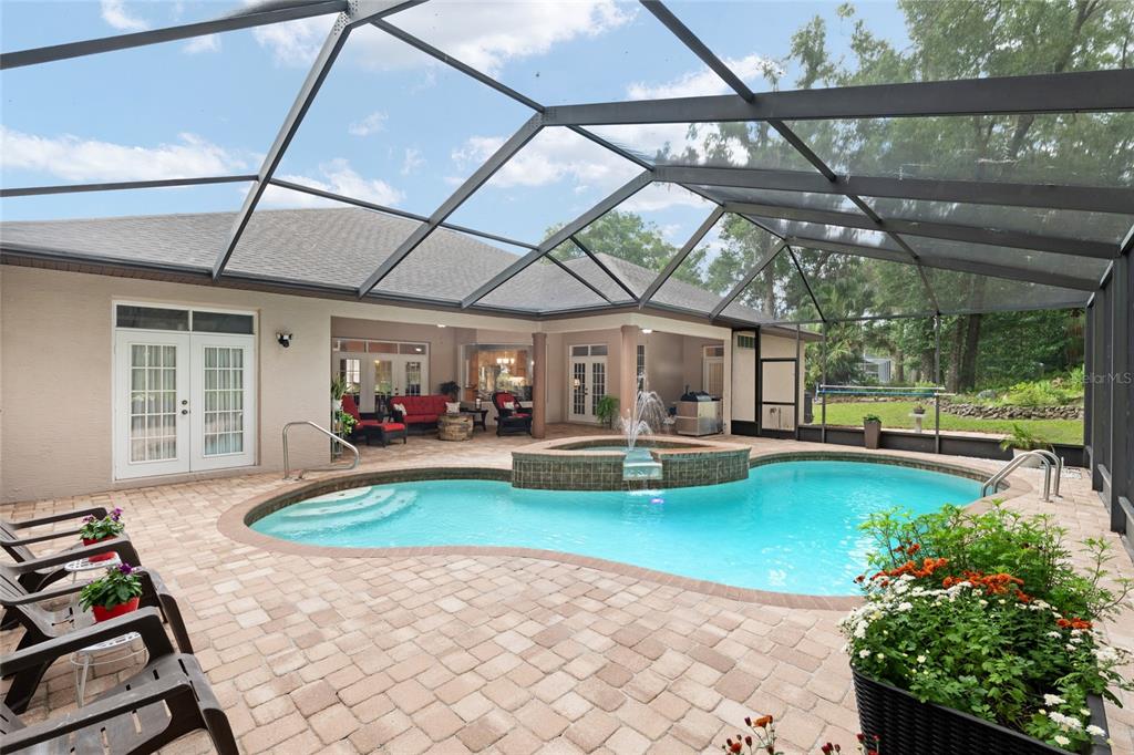 A screened-in patio features a swimming pool with a raised spa and brick pavers — 19654 SW 88TH LOOP, DUNNELLON, FL
