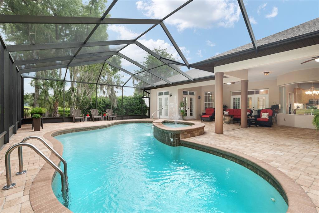 A screened-in patio features a swimming pool with a built-in fountain and brick pavers — 19654 SW 88TH LOOP, DUNNELLON, FL