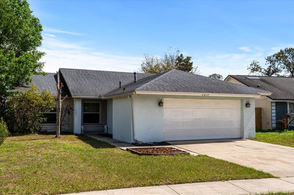 A single-story house with a light blue exterior, a two-car garage, and a shingled roof — 2019 PAPRIKA DRIVE, ORLANDO, FL