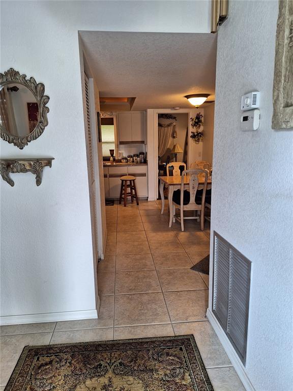 A tiled hallway leads to a kitchen and dining area with a wooden table — 2223 TINKER STREET, PORT CHARLOTTE, FL