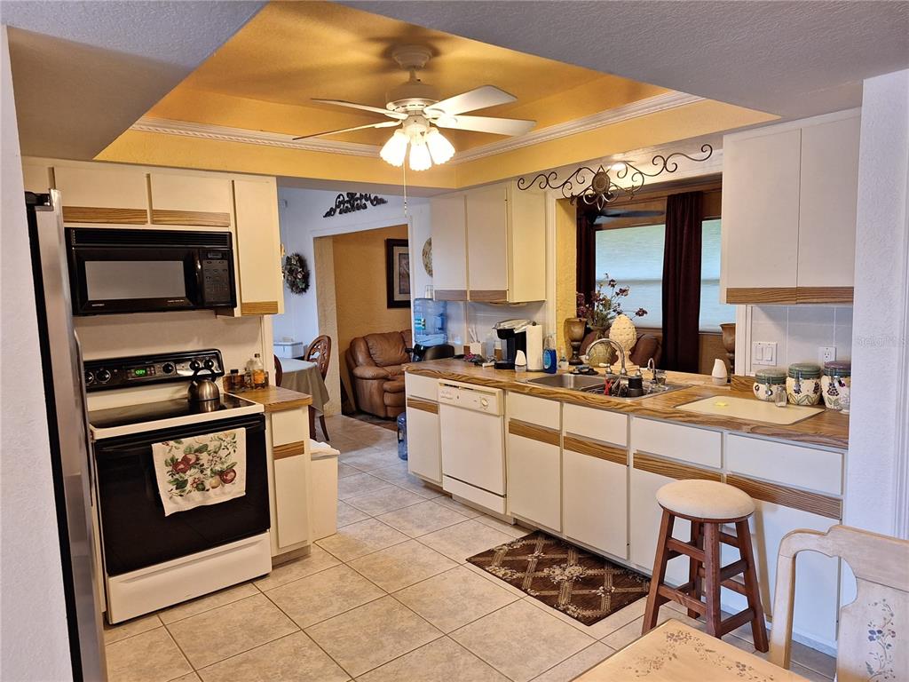 A kitchen with white cabinets, light countertops, tile flooring, and a ceiling fan — 2223 TINKER STREET, PORT CHARLOTTE, FL