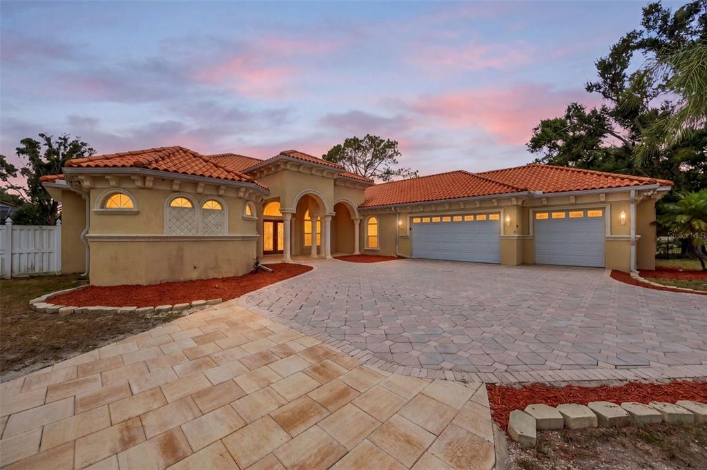 A single-story stucco house with a tile roof and a paved driveway at sunset — 8610 VIVIAN BASS WAY, ODESSA, FL