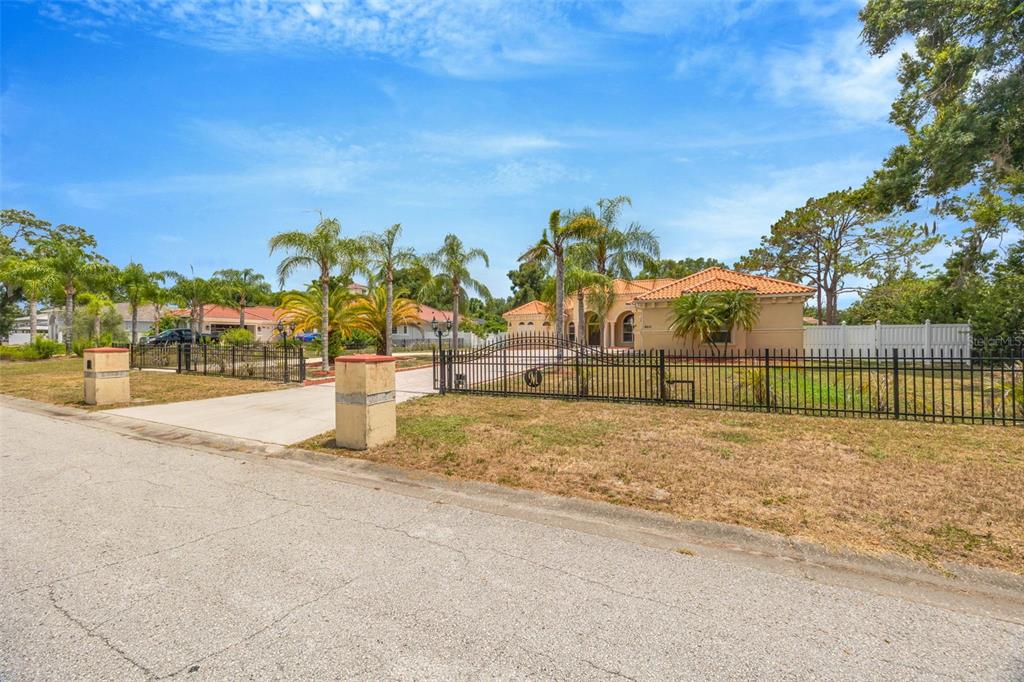 A single-story house with a tile roof sits behind a black metal fence and gate — 8610 VIVIAN BASS WAY, ODESSA, FL