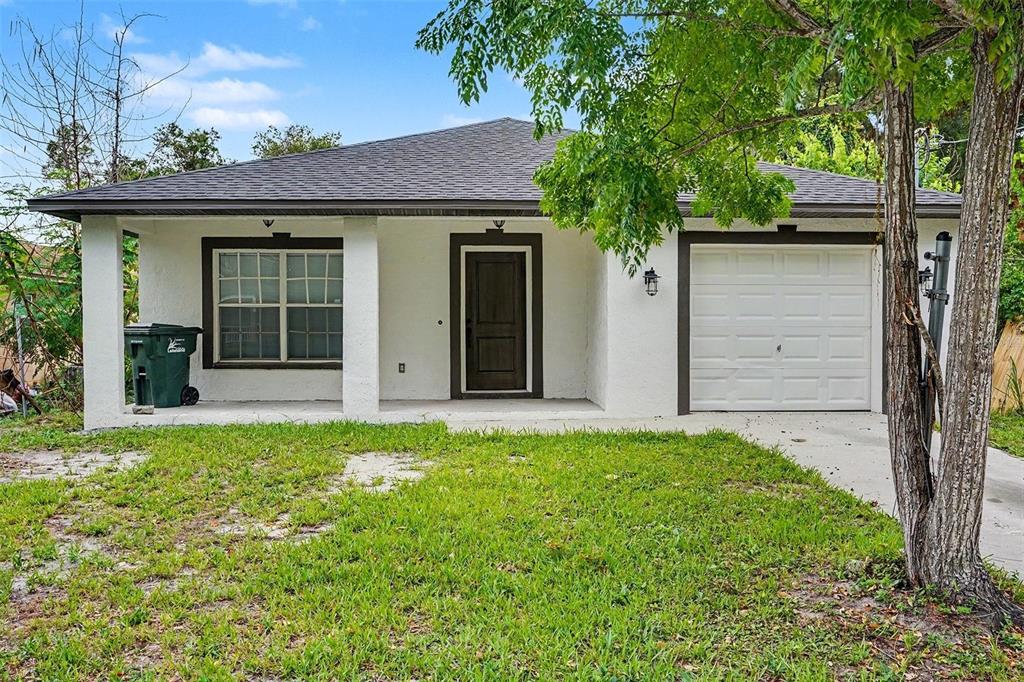 A single-story white house with a dark roof, front porch, and an attached garage — 1128 NEVILLE AVENUE, LAKELAND, FL