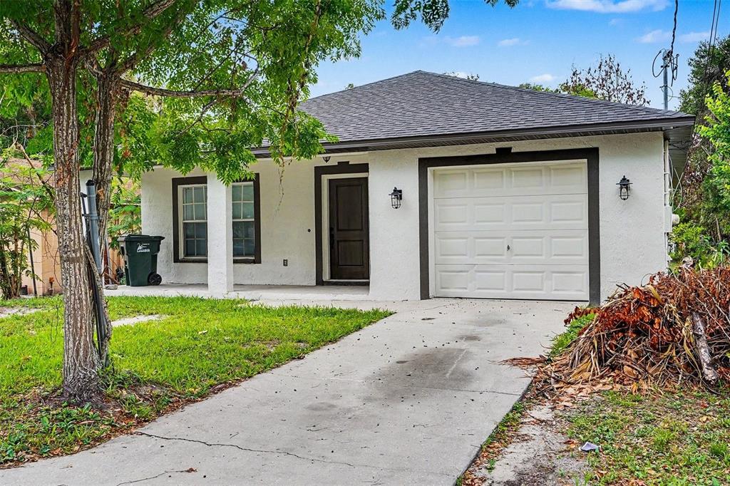 A white, single-story house with a dark-trimmed front door, garage, and a concrete driveway — 1128 NEVILLE AVENUE, LAKELAND, FL