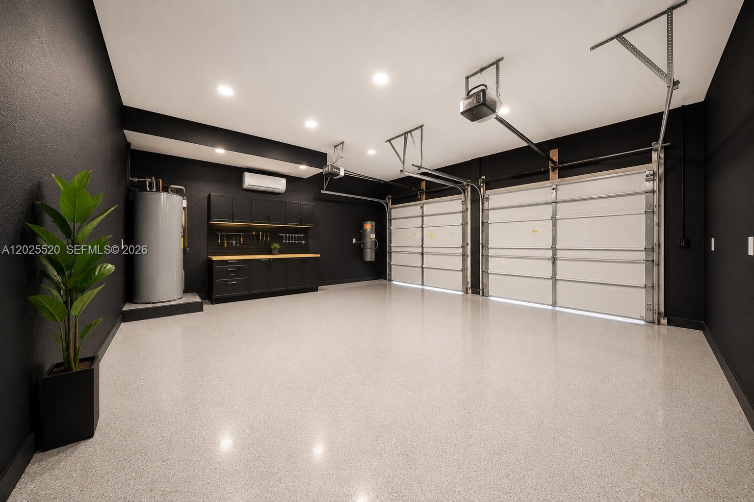 A modern two-car garage features black walls, white garage doors, and a speckled epoxy floor — 15721 NW 79th Ct, Miami Lakes FL 33016, MIAMI LAKES, FL