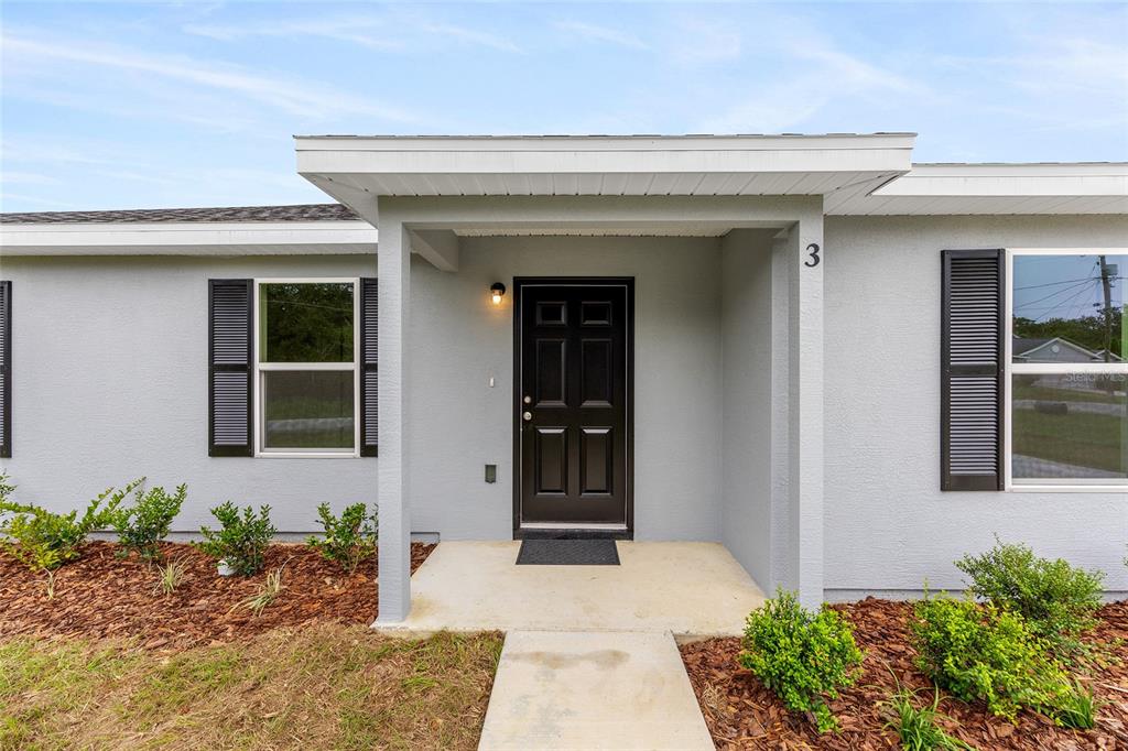 The exterior of a house features a covered entryway, a black front door, and shutters — 229 LOCUST LANE, OCALA, FL
