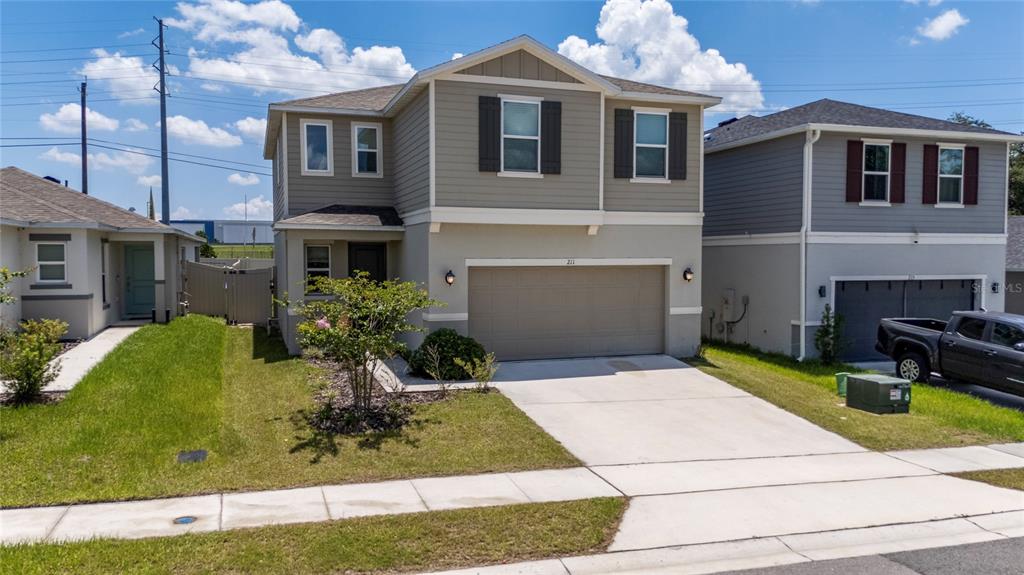 A two-story suburban house with a beige stucco lower level, gray siding, and a garage — 211 ASH WAY, AUBURNDALE, FL