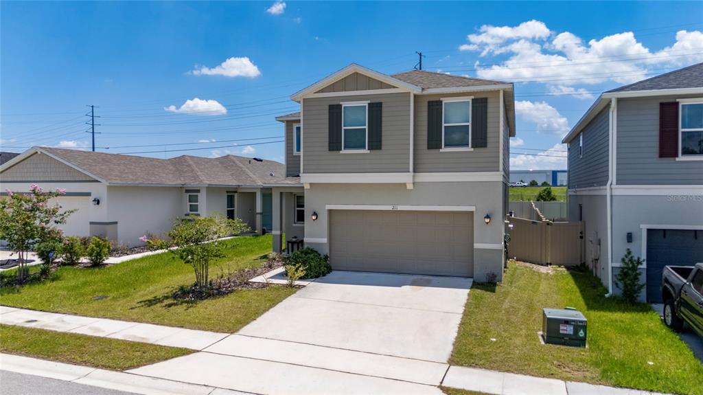 A two-story suburban house features a tan stucco lower level and gray siding above — 211 ASH WAY, AUBURNDALE, FL