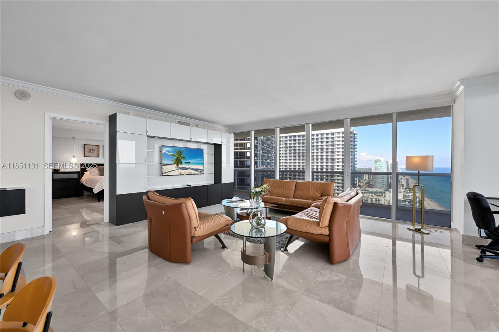 A living room features tan leather furniture, a large media wall, and floor-to-ceiling ocean views — 1830 S Ocean Dr # 3801, Hallandale Beach FL 33009, HALLANDALE BEACH, FL