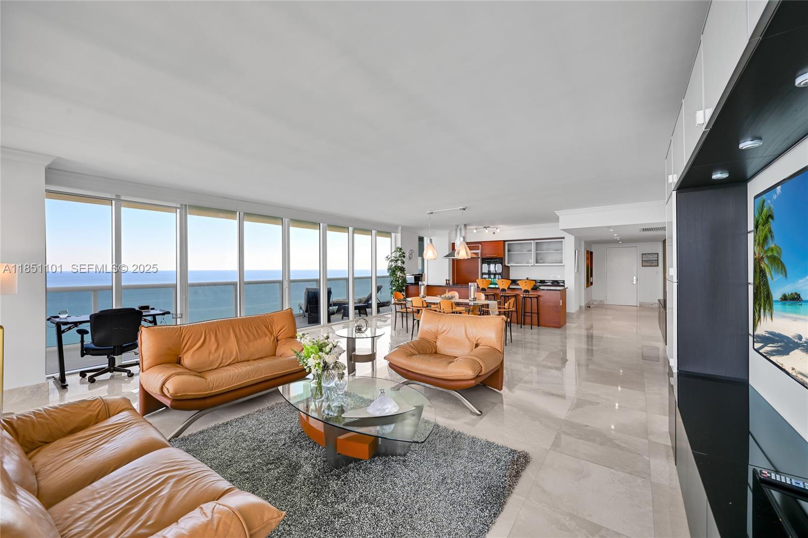 An open-concept living and dining area features leather furniture, tile floors, and floor-to-ceiling ocean views — 1830 S Ocean Dr # 3801, Hallandale Beach FL 33009, HALLANDALE BEACH, FL
