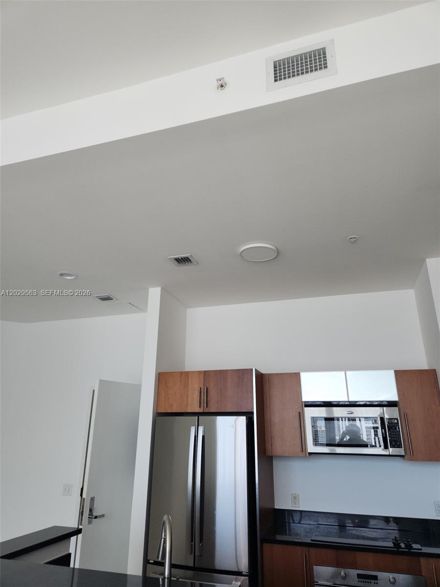 A modern kitchen features dark wood cabinetry, stainless steel appliances, and recessed ceiling lighting — 300 S Biscayne Blvd # 3807, Miami FL 33131, MIAMI, FL
