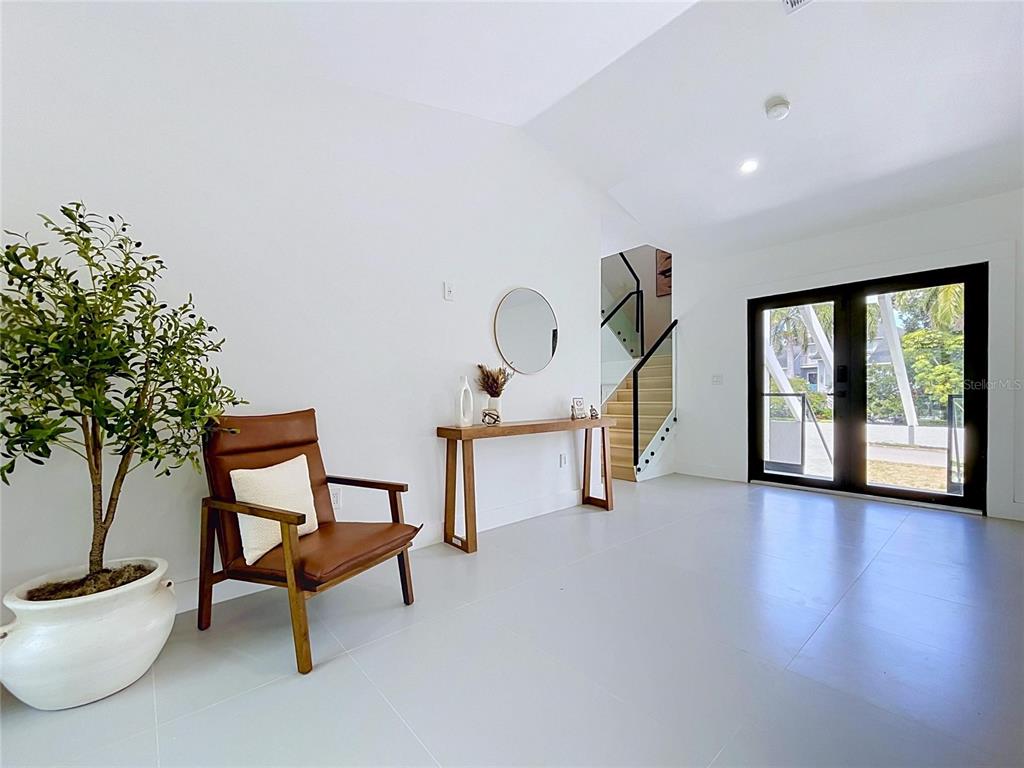 A minimalist room features a brown leather chair, a console table, and a staircase — 807 2ND AVENUE S, TIERRA VERDE, FL