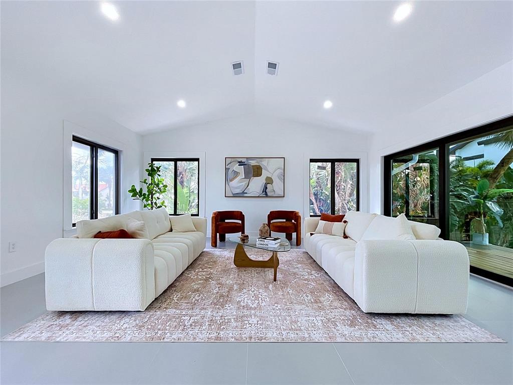 A bright living room features two white sofas, a patterned rug, and large windows — 807 2ND AVENUE S, TIERRA VERDE, FL