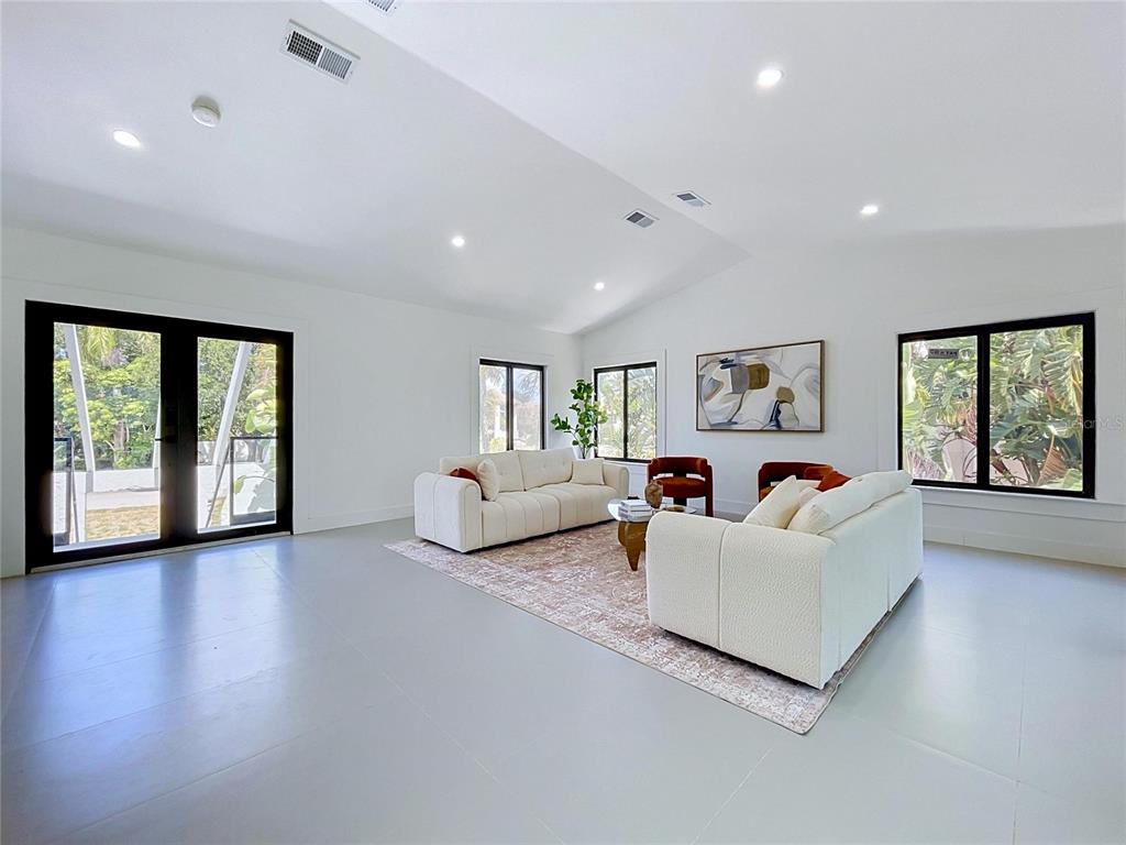 A bright living room features white walls, light tile floors, and a vaulted ceiling — 807 2ND AVENUE S, TIERRA VERDE, FL