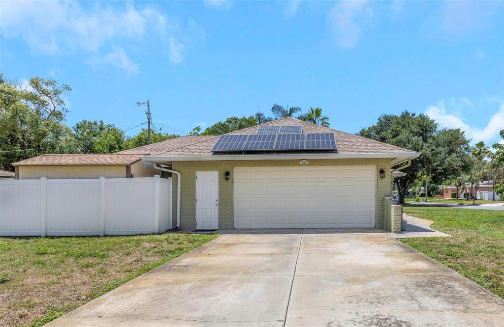 A detached garage with solar panels on the roof and a white vinyl fence — 2465 BURNICE DRIVE, CLEARWATER, FL