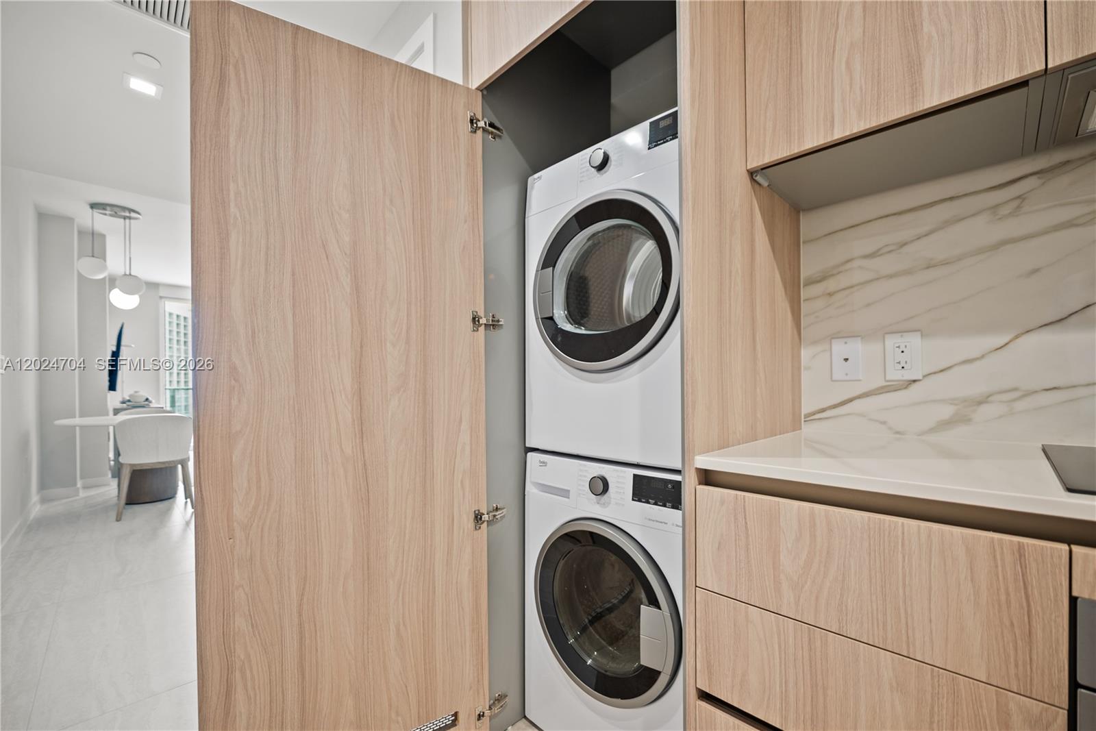 A stacked washer and dryer unit is built into a light wood kitchen cabinet — 77 SE 5th Street # 1604, Miami FL 33131, MIAMI, FL