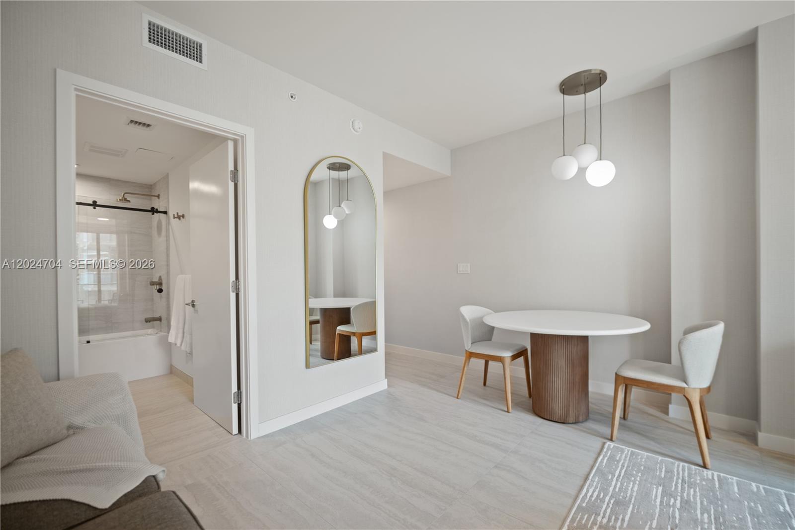 A dining area with a round table, two chairs, and an arched wall mirror — 77 SE 5th Street # 1604, Miami FL 33131, MIAMI, FL