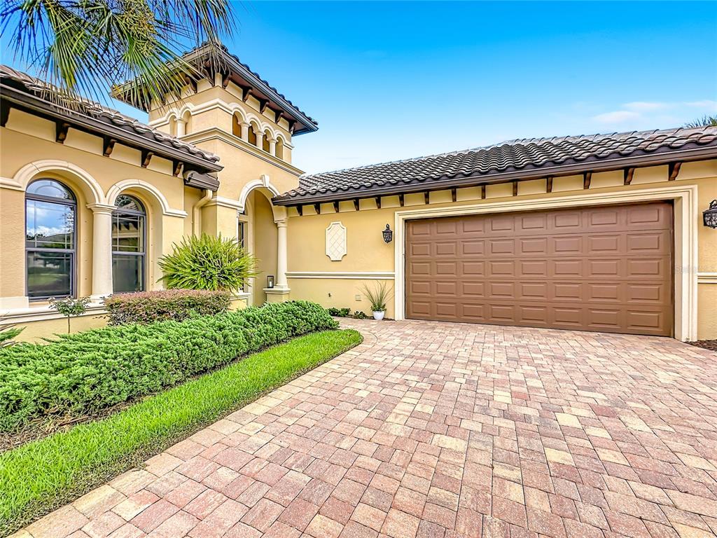 The exterior of a Mediterranean-style home features a paved driveway, a garage, and landscaping — 341 HIBISCUS WAY, PALM COAST, FL