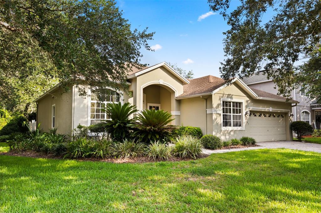 A single-story house with a beige stucco exterior, a two-car garage, and landscaped front yard — 3289 RED ASH CIRCLE, OVIEDO, FL