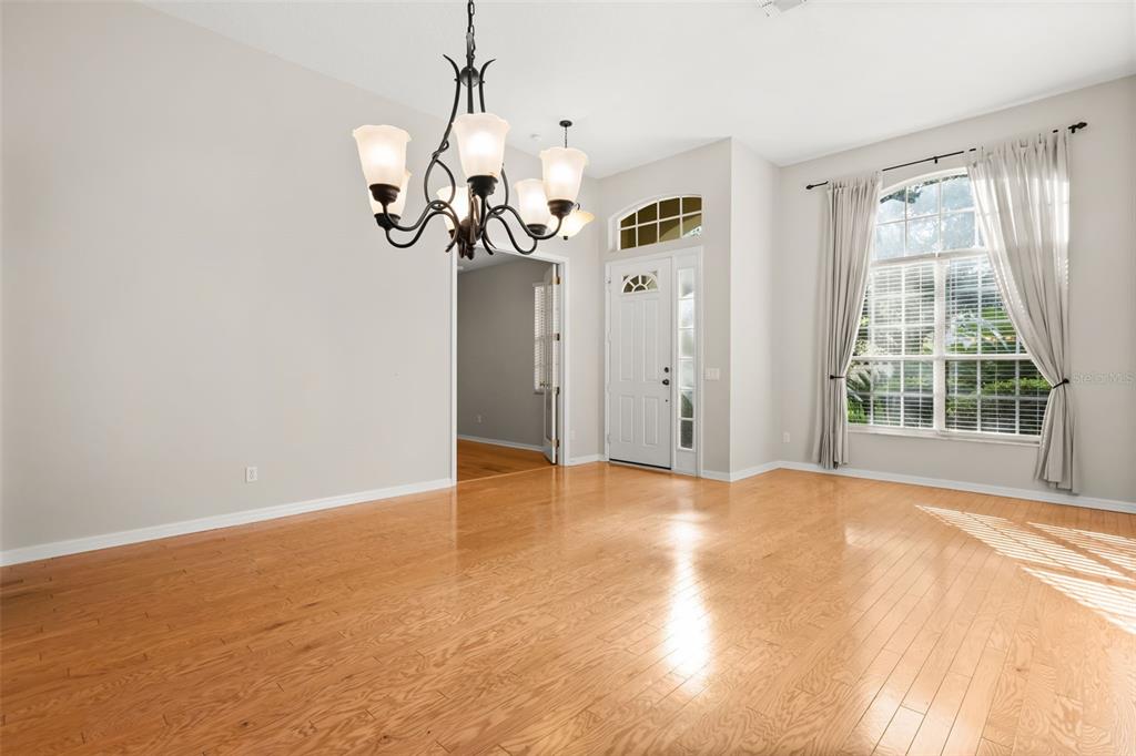 A dining room with hardwood floors, a chandelier, and a front door with sidelights — 3289 RED ASH CIRCLE, OVIEDO, FL