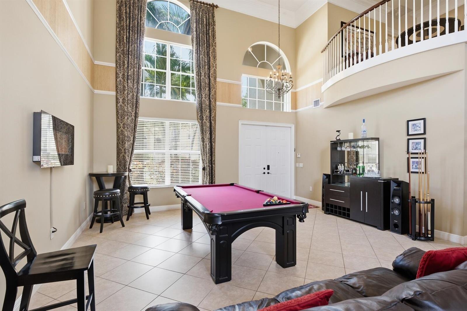 A high-ceilinged game room features a purple pool table, a bar, and tile flooring — 11161 Sunset Ridge Circle, Boynton Beach FL 33473, BOYNTON BEACH, FL