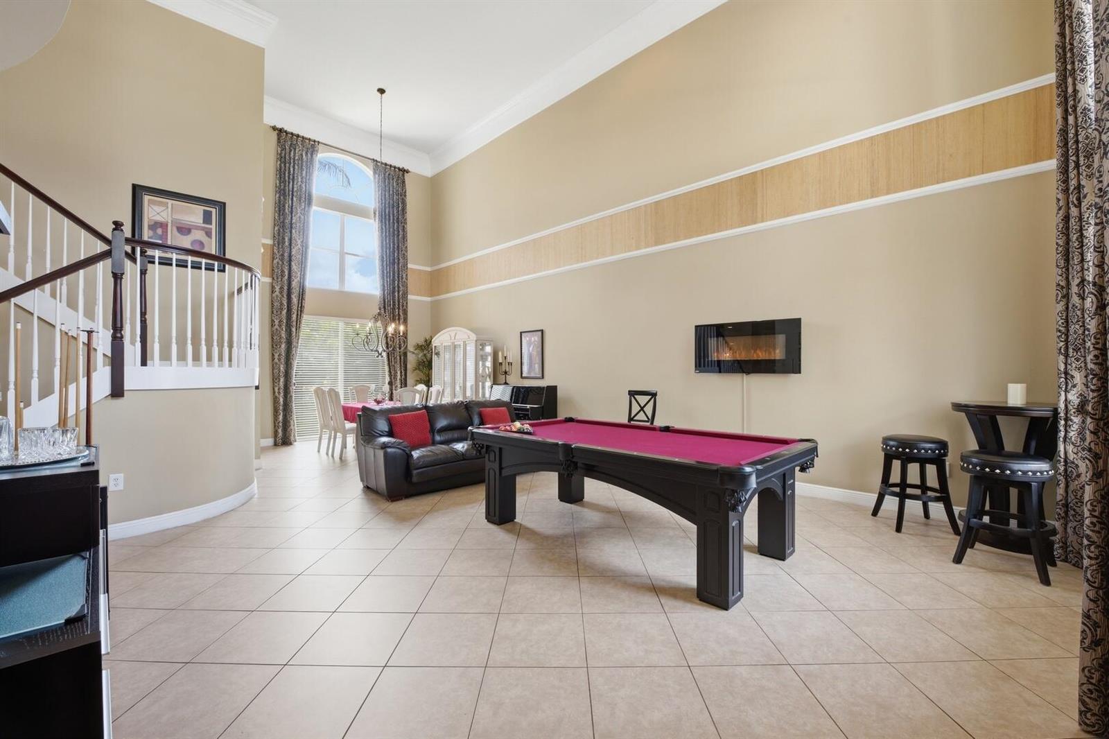 A spacious room with tile floors, a pool table, a fireplace, and a curved staircase — 11161 Sunset Ridge Circle, Boynton Beach FL 33473, BOYNTON BEACH, FL