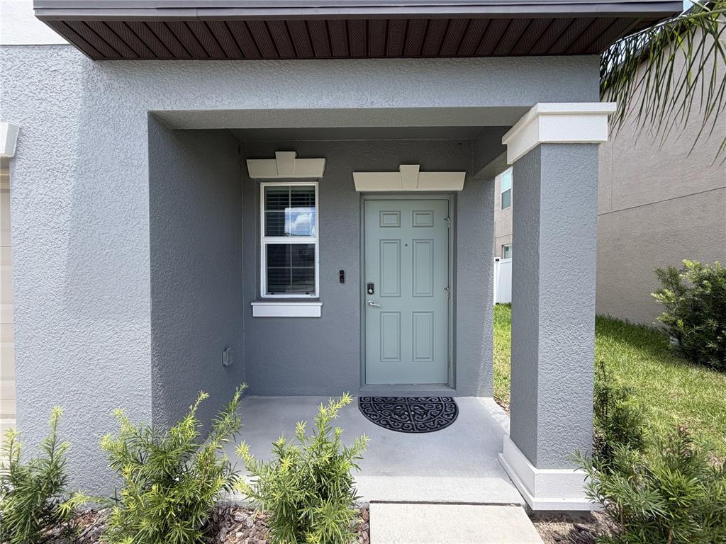 A gray house exterior features a light green front door and a small covered porch — 156 ROSE BUD LANE, SPRING HILL, FL