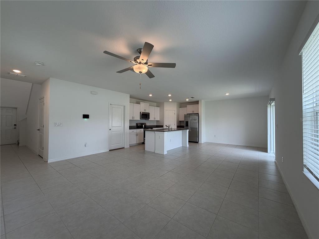An open-concept kitchen and living area features white cabinets, a center island, and tile flooring — 156 ROSE BUD LANE, SPRING HILL, FL